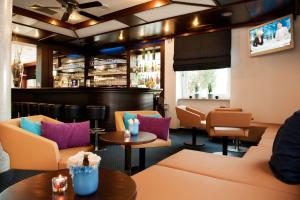 a restaurant with couches and tables and a bar at ACHAT Hotel Regensburg im Park in Regensburg