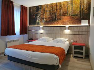 a bedroom with a large bed with a painting on the wall at Hotel Au Parc des Cigognes in Kintzheim