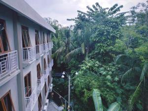 een balkon met uitzicht op een gebouw met bomen bij The Sarining Hotel in Tabanan