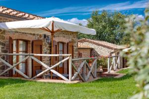 una casa in pietra con un ombrello nell'erba di Tenuta di Montecucco - ColleMassari Hospitality a Cinigiano