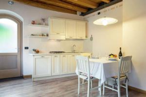 uma cozinha com mesa e cadeiras e uma cozinha com armários brancos em 1 bedroom ground floor apartment with private garden em Miane