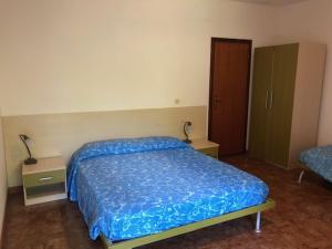 1 dormitorio con 1 cama azul y 2 mesitas de noche en Agriresidence San Pietro, en Bibione