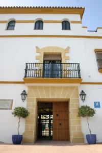 - un bâtiment avec une porte en bois et un balcon dans l'établissement Mesón de la Molinera, à Arcos de la Frontera
