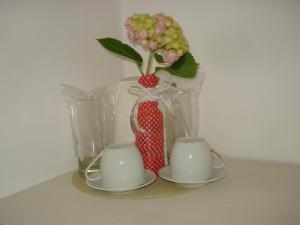 una mesa con un jarrón con una flor y dos tazas en Kupenova Guest House, en Sozopol