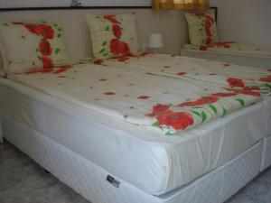 Una gran cama blanca con flores rojas. en Kupenova Guest House, en Sozopol