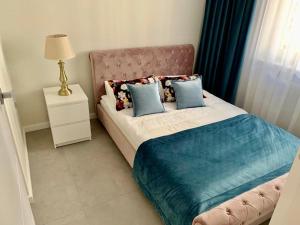 een slaapkamer met een groot bed met blauwe kussens bij Apartament Jantarowe Zacisze Rose in Jantar