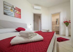 a bedroom with a red and white bed with towels on it at Casa vacanze IL MANDORLO in Scicli +35 photos