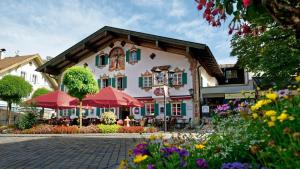 Un edificio con sombrillas y flores delante. en Hotel Alte Post, en Oberammergau