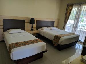 a hotel room with two beds and a window at Hotel Pondok Asri Tawangmangu in Tawangmangu