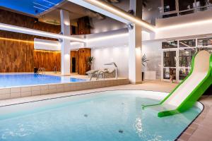 a swimming pool with a blue tub and a blue chair at Hotel Jantar Wellness & Spa in Ustka