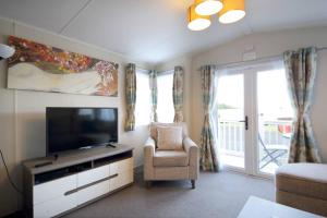 a living room with a television and a chair at Edinburgh - Seton Sands-Cameo Caravan-Pet Friendly in Edinburgh
