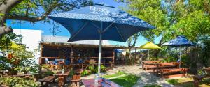 um guarda-chuva azul em frente a um restaurante com mesas e bancos em Palm Cottage - Colchester - 5km from Elephant Park em Colchester