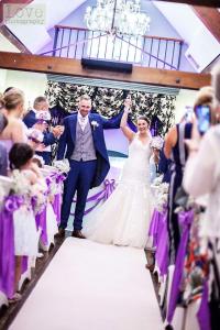 a bride and groom walking down the aisle at their wedding at The Barns Hotel in Cannock