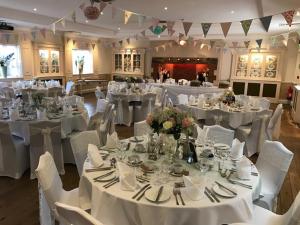 a banquet hall with white tables and white chairs at The Barns Hotel in Cannock