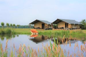 a couple of tents sitting on the side of a lake at Safaritenten 'Woody' in Kuinre