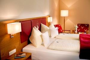 two beds in a hotel room with red and white pillows at Hotel Kerschbaumer in Russbach am Pass Gschütt