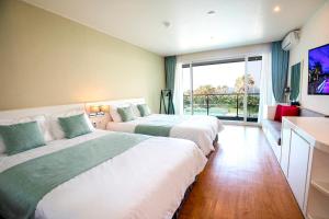 two beds in a hotel room with a large window at The Four Grace Resort in Seogwipo +38 photos