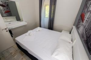 a small room with a white bed and a mirror at Ifigenia's Apartments in Stoupa +58 photos