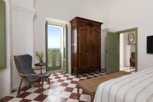 a bedroom with a bed and a chair and a window at Rocco Forte Masseria Torre Maizza in Savelletri di Fasano