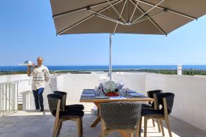 a man standing on a balcony with a table with an umbrella at Rocco Forte Masseria Torre Maizza in Savelletri di Fasano