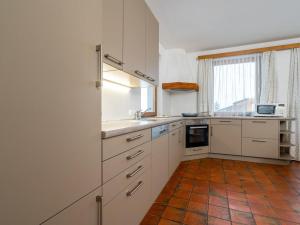 kuchnia z białymi szafkami i podłogą wyłożoną kafelkami w obiekcie Appartements Maurer w mieście Flachau