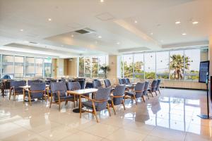 een conferentiezaal met tafels, stoelen en ramen bij The Four Grace Resort in Seogwipo