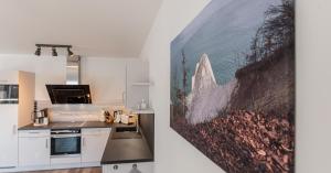 eine Küche mit weißen Schränken und einem Wandgemälde in der Unterkunft Ferienwohnung Vergissmeinnicht in Ostseebad Sellin
