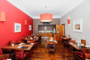 uma sala de jantar com mesas de madeira e paredes vermelhas em Kelvingrove Hotel - Sauchiehall St em Glasgow