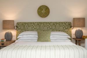 a bedroom with a bed with a green headboard and two lamps at Rocco Forte Masseria Torre Maizza in Savelletri di Fasano