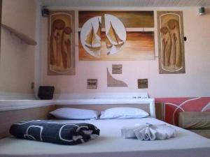 Cama en habitación con pinturas en la pared en OYO TBS Hotel, en Manacapuru