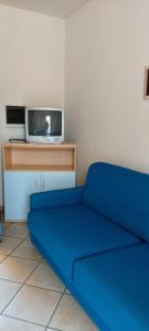 a blue couch in a room with a tv at Residence Leonardo in Lido di Spina