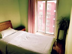 una camera con un letto bianco e una finestra di LETE Hostel a Xining