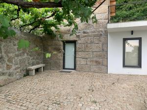 a stone building with a bench next to a door at Casa AURORA in Amarante
