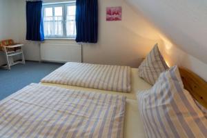 a bedroom with two beds and a window with blue curtains at Ferienwohnung Regina in Dornum