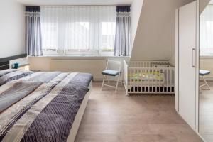 - une chambre avec un lit, un lit bébé et des fenêtres dans l'établissement Ferienhaus Kormoran, à Dornumersiel