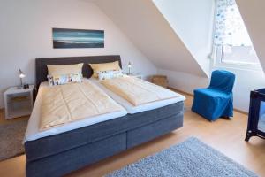 ドルヌマージールにあるFerienhaus Inselrosenのベッドルーム(大型ベッド1台、青い椅子付)