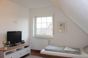 a living room with a tv and a window at Ferienhaus Strandruhe in Dornumersiel