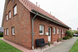a brick building with a black chair in front of it at Ferienhaus Strandruhe in Dornumersiel