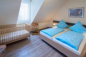 ドルヌマージールにあるFerienhaus Sieleckのベッドルーム1室(青い枕とベビーベッド付)