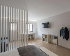 a white room with a bed and a television on the wall at Dom Pipas Houses - Batista & Marcelino Lda in Sintra