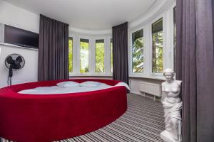 a bedroom with a large red bed and a statue at A.V. namai in Palanga