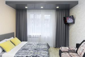 ノヴォシビルスクにあるCentral Apartment near by Marriott hotelのベッドルーム(ベッド1台、テレビ、ソファ付)