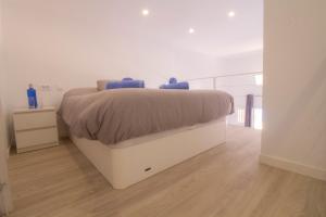 un letto bianco in una camera da letto bianca con pavimento in legno di MEDANO4YOU The Loft 007 a El Médano