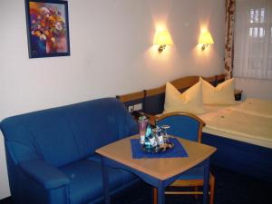 a hotel room with a blue chair and a bed at Landhotel Eulkretscham in Euldorf