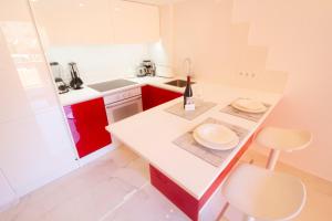 una cucina con bancone bianco e armadi rossi di MEDANO4YOU The Loft 007 a El Médano