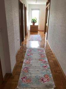 a hallway with a rug on the floor and a hallway with a flower rug at Sobe Lara in Gradačac