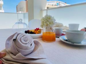 a table with a plate of food and a bowl of orange juice at Elite Boutique Hotel in Roseto degli Abruzzi +14 photos