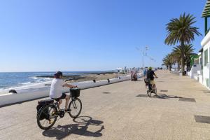 two people riding bikes down a sidewalk near the beach at ALIZUTH HOME in Playa Honda