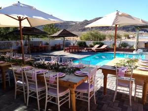 a table with chairs and umbrellas next to a pool at Daisy Country Lodge in Springbok