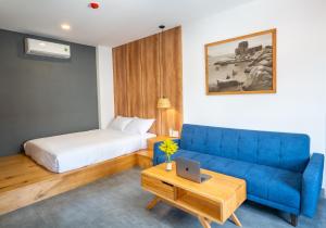 a living room with a blue couch and a bed at Coast House Boutique Hotel in Nha Trang